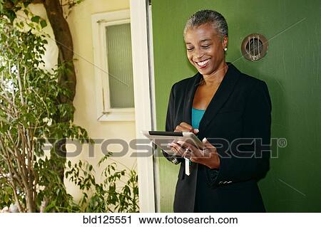 Stock Image - Black businesswoman using digital tablet outdoors. Fotosearch