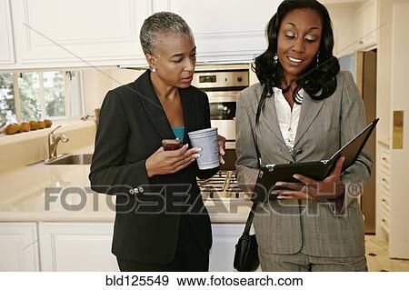 Stock Photo - Black businesswomen talking in kitchen. Fotosearch