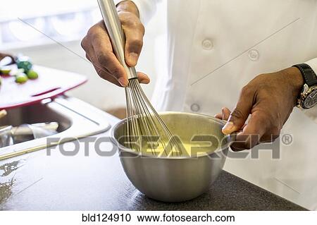 Stock Image - Black chef whisking eggs in restaurant. Fotosearch