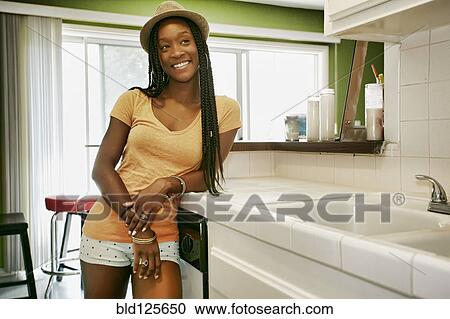 Stock Image - Black woman smiling in kitchen. Fotosearch