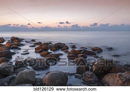 Stock Photo - Blurred ocean washing over rocks. Fotosearch