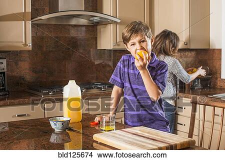 Boy eating fruit in kitchen View Large Photo Image Picture - Boy eating fruit in kitchen. Fotosearch
