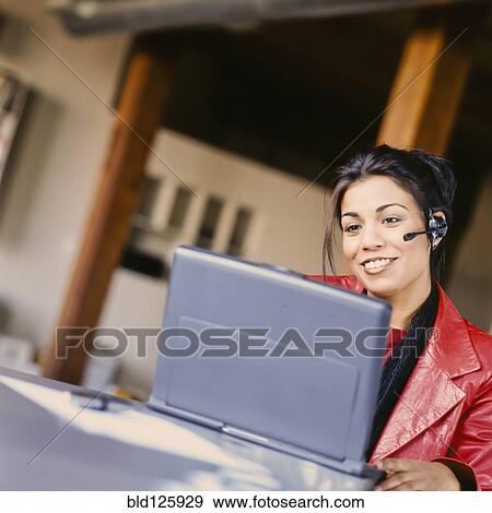 Businesswoman talking on headset in office View Large Photo Image Stock Photo - Businesswoman talking on headset in office. Fotosearch