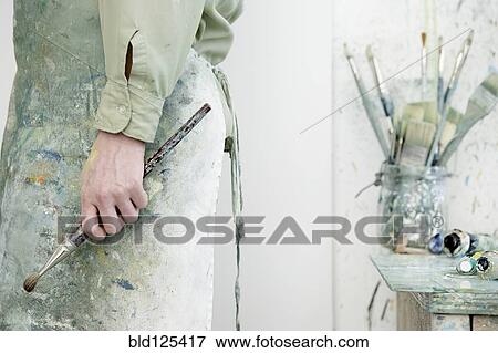 Stock Photo - Caucasian artist holding paintbrush in studio. Fotosearch