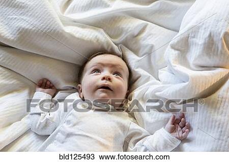 Stock Image - Caucasian baby boy laying in bed. Fotosearch