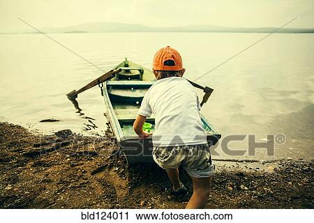 Caucasian boy pushing boat into still lake View Large Photo Image Stock Image - Caucasian boy pushing boat into still lake. Fotosearch
