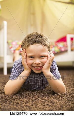 Stock Image - Caucasian boy smiling in bedroom. Fotosearch