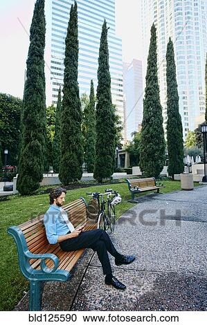 Stock Image - Caucasian businessman relaxing in urban park. Fotosearch
