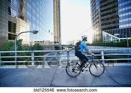 Stock Photograph - Caucasian businessman riding bicycle on urban street. Fotosearch