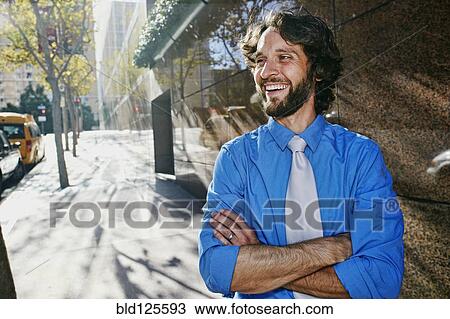 Stock Image - Caucasian businessman smiling on city street. Fotosearch