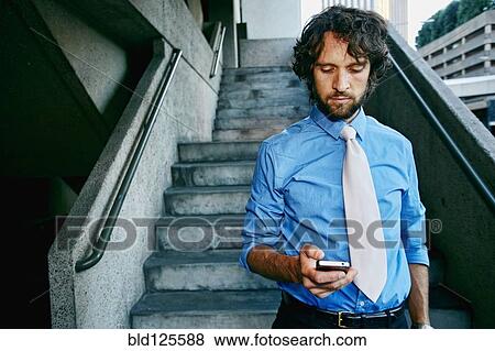 Stock Photo - Caucasian businessman using cell phone on urban stairs. Fotosearch