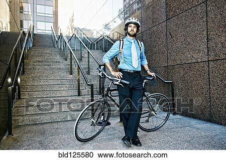 Stock Image - Caucasian businessman with bicycle on urban stairs. Fotosearch