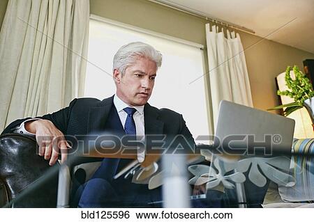 Stock Photograph - Caucasian businessman working in living room. Fotosearch