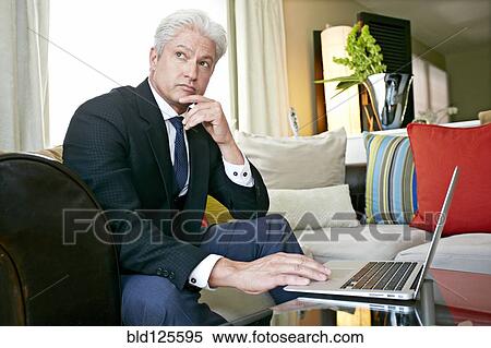 Stock Photography - Caucasian businessman working in living room. Fotosearch