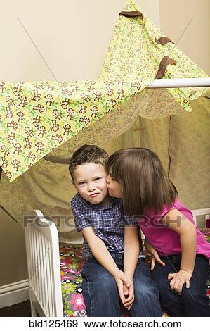 Stock Photo - Caucasian children kissing in blanket fort. Fotosearch