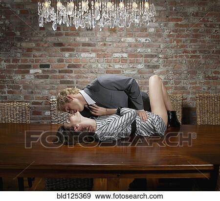 Stock Photo - Caucasian couple kissing seductively on table. Fotosearch