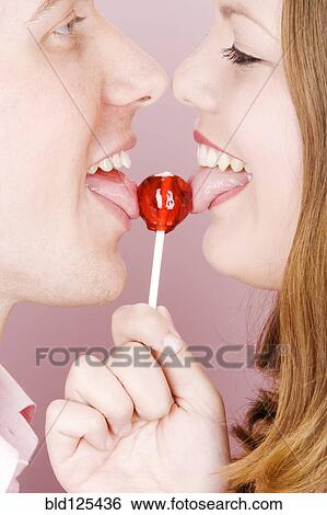 Caucasian couple licking lollipop View Large Photo Image Stock Photograph - Caucasian couple licking lollipop. Fotosearch
