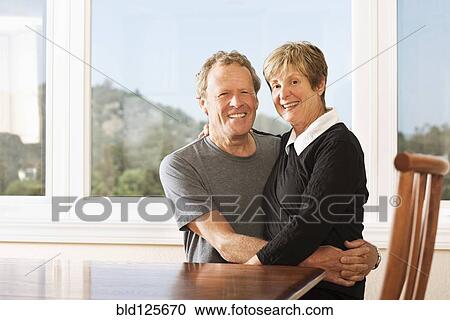 Stock Image - Caucasian couple smiling together at kitchen table. Fotosearch
