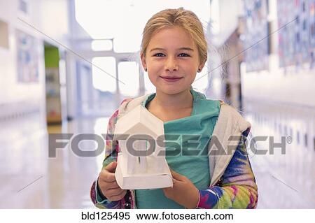 Stock Photography - Caucasian girl holding art project in school corridor. Fotosearch