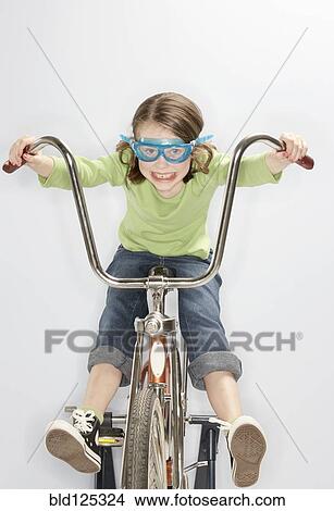 Picture - Caucasian girl riding bicycle in goggles. Fotosearch