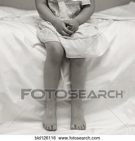 Stock Photograph - Caucasian girl sitting on bed. Fotosearch