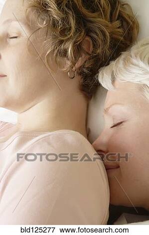 Stock Photo - Caucasian lesbian couple sleeping on bed. Fotosearch