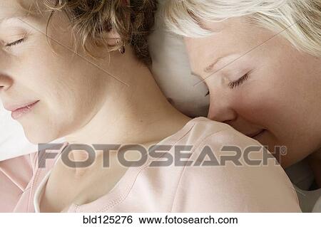 Stock Photograph - Caucasian lesbian couple sleeping on bed. Fotosearch