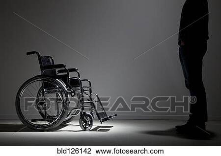 Stock Image - Caucasian man approaching wheelchair. Fotosearch