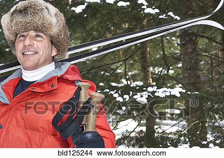 Caucasian man carrying skis in snowy landscape View Large Photo Image Picture - Caucasian man carrying skis in snowy landscape. Fotosearch