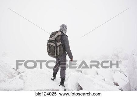 Stock Photography - Caucasian man hiking in snow. Fotosearch