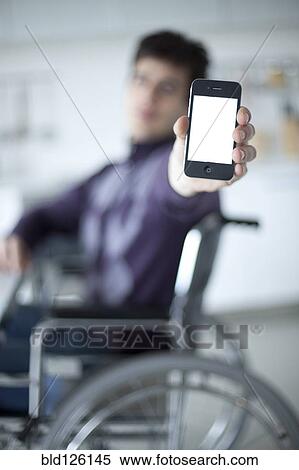 Stock Photography - Caucasian man in wheelchair holding cell phone. Fotosearch