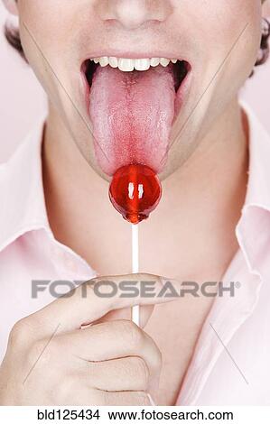 Picture - Caucasian man licking lollipop. Fotosearch
