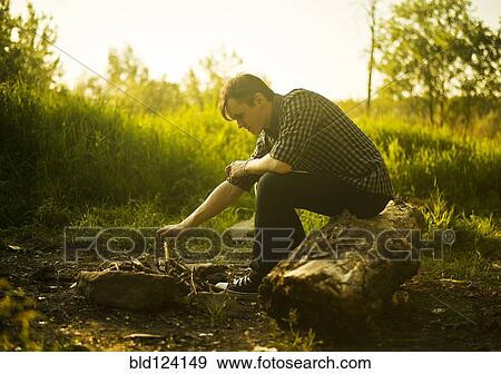 Caucasian man lighting campfire in rural field View Large Photo Image Stock Photo - Caucasian man lighting campfire in rural field. Fotosearch