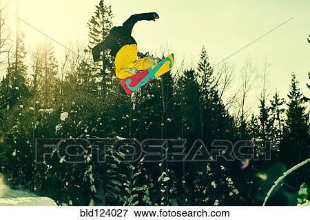 Stock Photo - Caucasian man mid-air on snowboard. Fotosearch