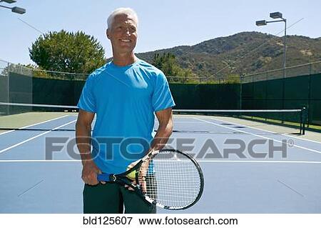 Stock Photo - Caucasian man smiling on tennis court. Fotosearch