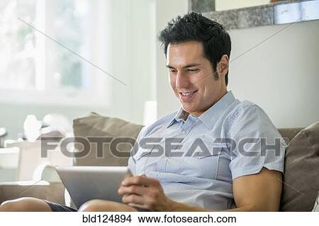 Caucasian man using digital tablet on sofa View Large Photo Image Picture - Caucasian man using digital tablet on sofa. Fotosearch