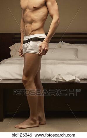 Stock Photography - Caucasian man wearing underwear in bedroom . Fotosearch