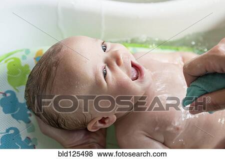 Stock Photo - Caucasian mother giving baby boy a bath. Fotosearch