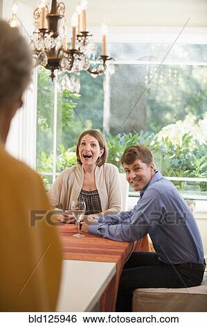 Stock Photograph - Caucasian mother surprising couple at table. Fotosearch