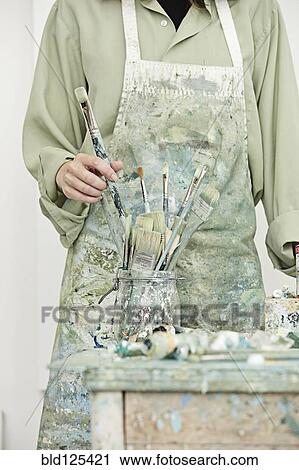 Stock Image - Caucasian painter working in studio. Fotosearch