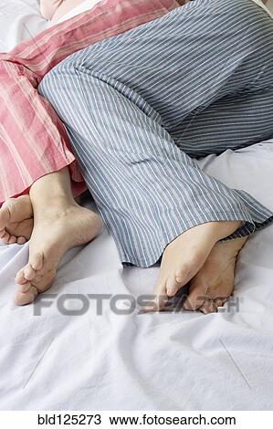 Stock Image - Caucasian pregnant lesbian couple laying on bed. Fotosearch