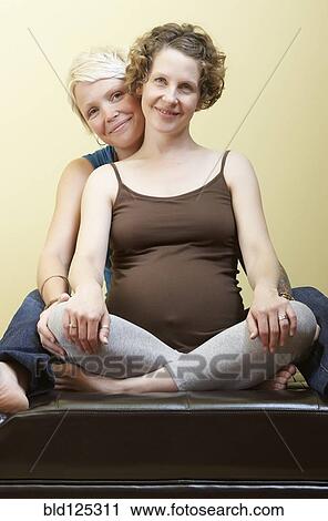 Stock Image - Caucasian pregnant lesbian couple smiling. Fotosearch