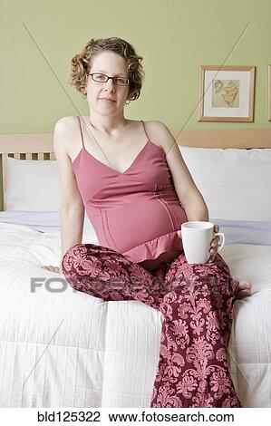 Caucasian pregnant woman drinking cup of coffee on bed View Large Photo Image Stock Image - Caucasian pregnant woman drinking cup of coffee on bed. Fotosearch