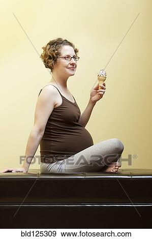 Caucasian pregnant woman eating ice cream cone View Large Photo Image Stock Photo - Caucasian pregnant woman eating ice cream cone. Fotosearch