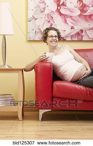 Caucasian pregnant woman having cup of coffee on sofa View Large Photo Image Stock Photo - Caucasian pregnant woman having cup of coffee on sofa. Fotosearch