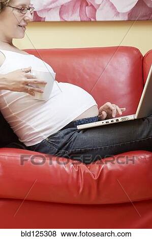 Caucasian pregnant woman using laptop on sofa View Large Photo Image Stock Photo - Caucasian pregnant woman using laptop on sofa. Fotosearch