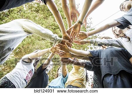 Stock Image - Caucasian teenagers putting hands together in huddle. Fotosearch