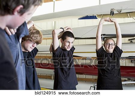 Stock Photography - Caucasian teenagers stretching in boathouse. Fotosearch