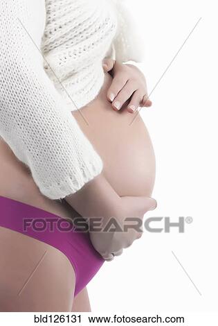 Stock Image - Caucasian woman holding pregnant belly. Fotosearch