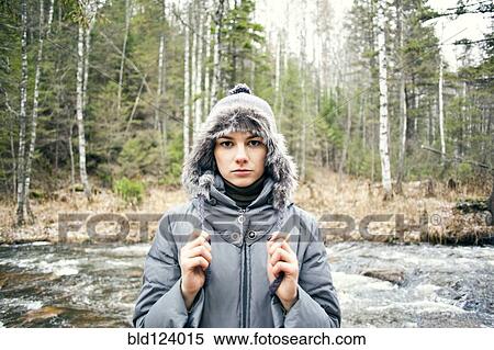 Stock Photography - Caucasian woman in coat standing by rural river. Fotosearch